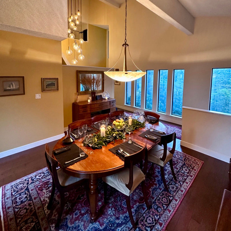 Dining room with a wooden table set for a meal, large windows, and decorative elements.