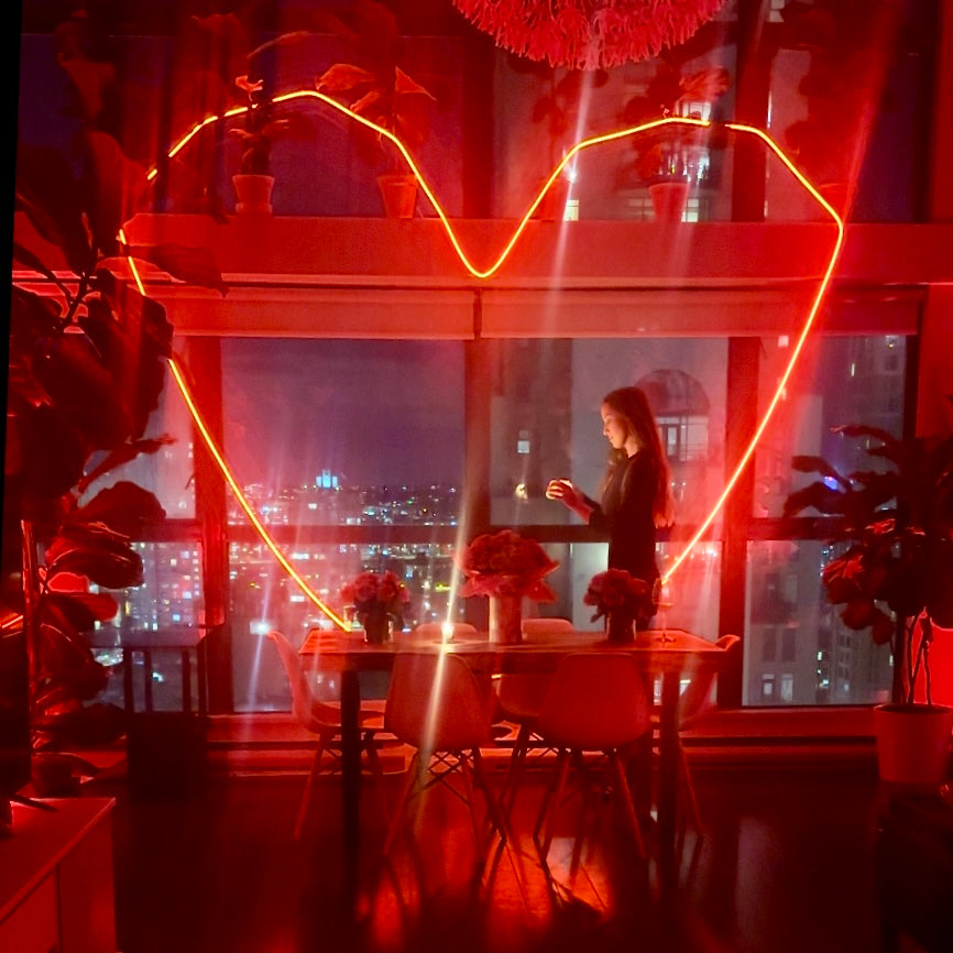 Woman standing in a modern kitchen with red lighting and cityscape view