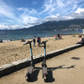 Bike path next to beach with people and mountains in the background