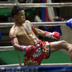 Boxer in action inside a boxing ring with visible branding on the ropes.