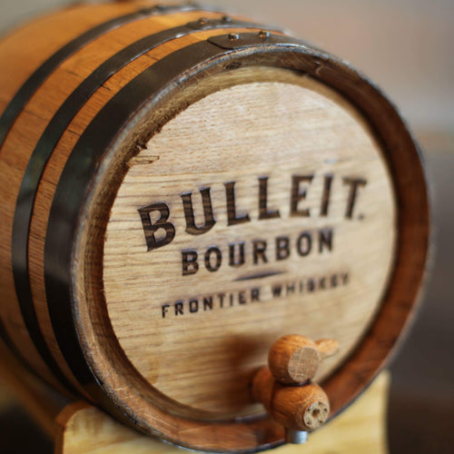 Bulleit Bourbon Frontier Whiskey barrel on a stand with a blurred background