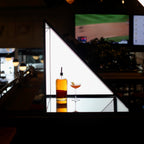 Bottle and glass of cocktail on a reflective surface with a blurred bar background