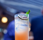 Cocktail with lime wedge and mint leaf in a glass against a blurred background