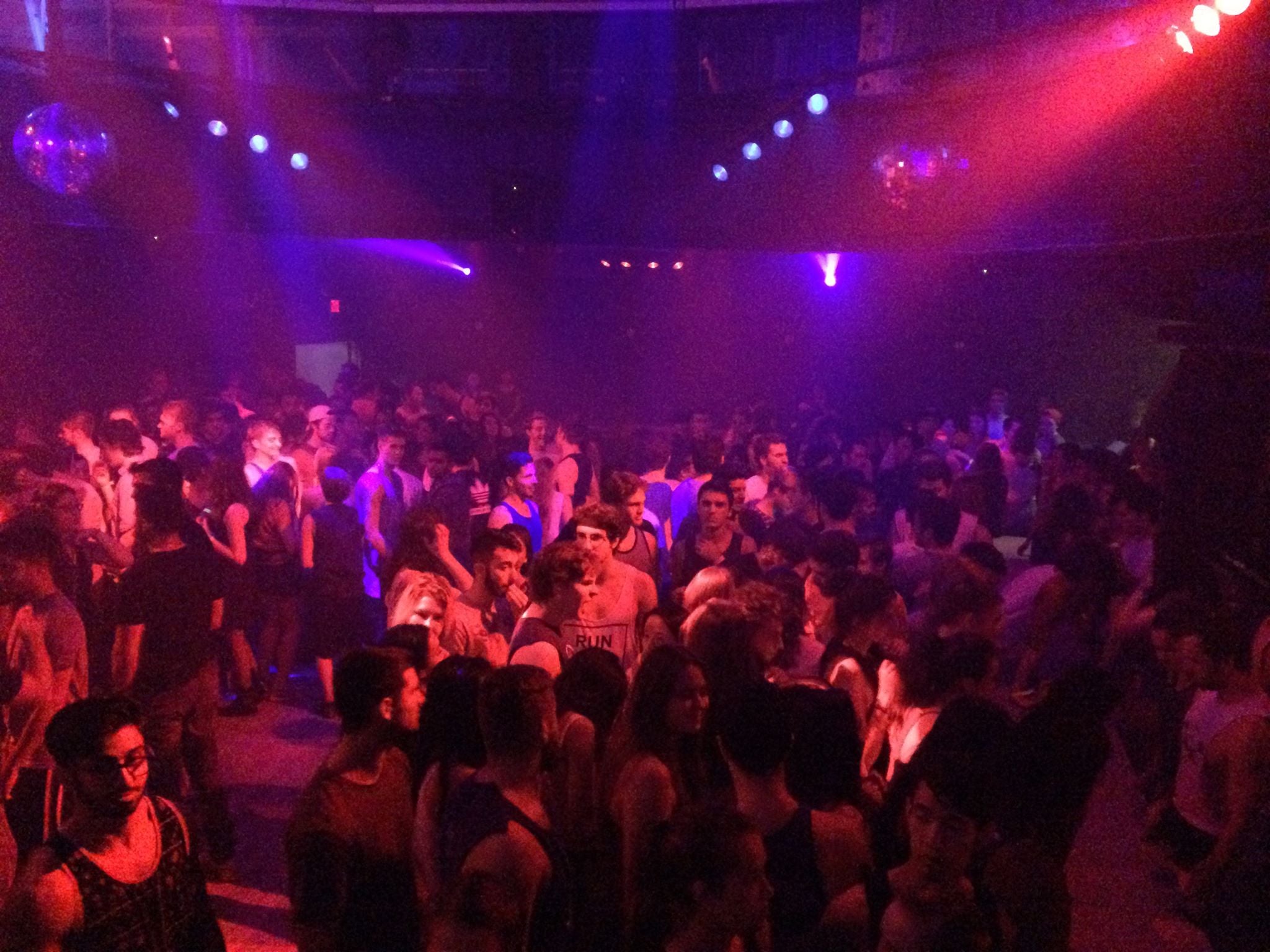 Crowded nightclub with people dancing under colorful lights shot by Evelyn Martin McGill faculty Olympics 