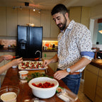 Two people preparing food in a kitchen with various items on the counter.