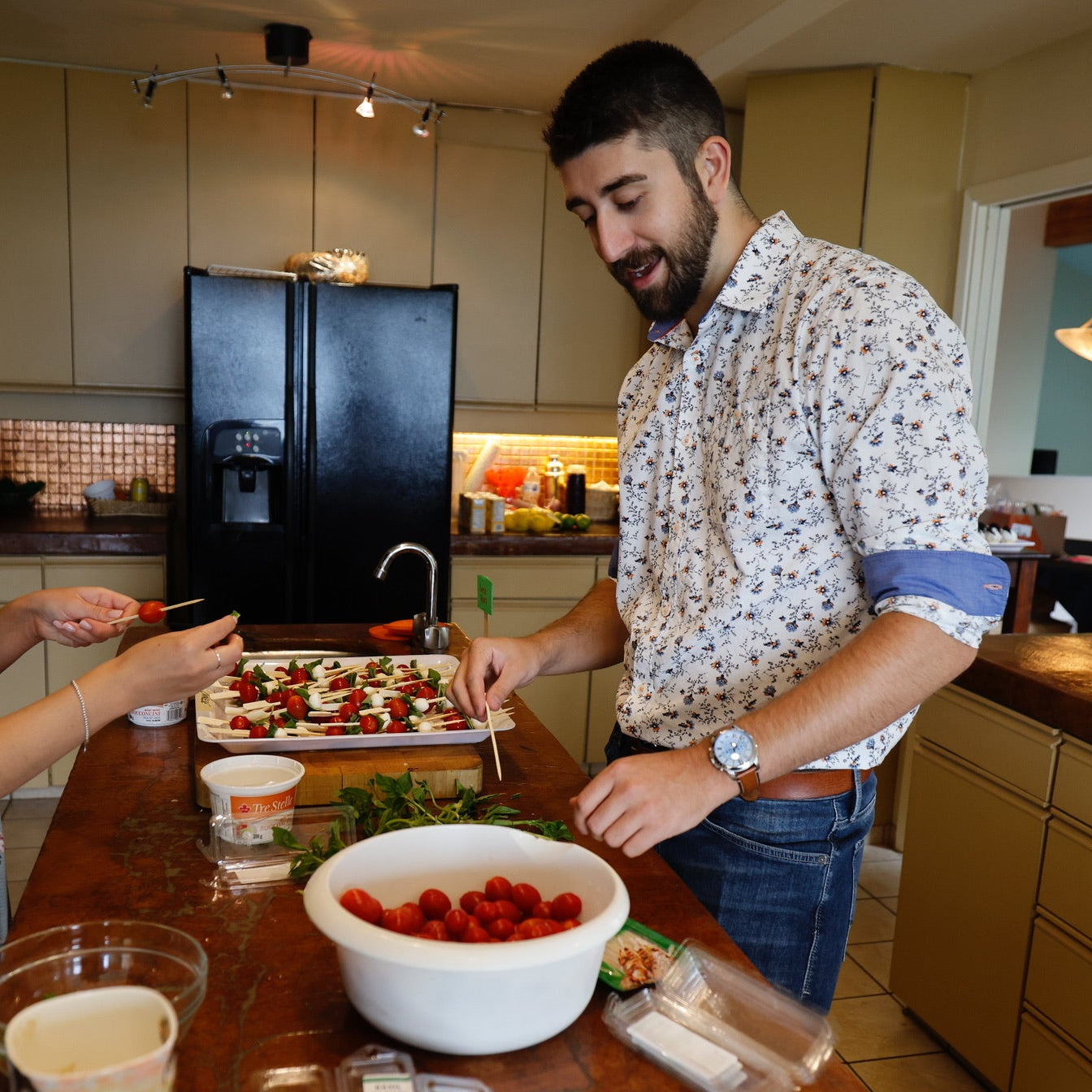 Two people preparing food in a kitchen with various items on the counter.