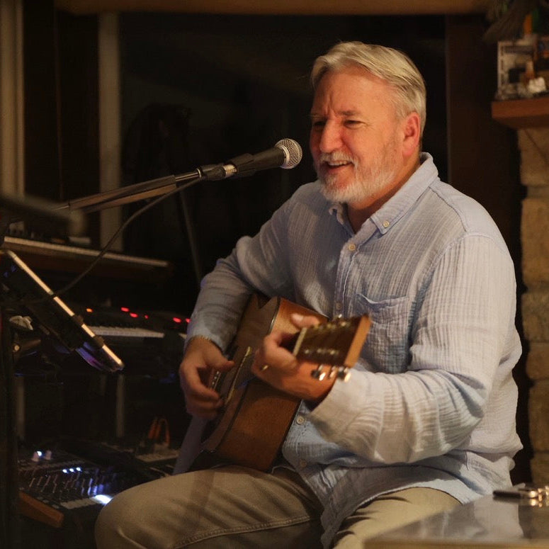 Man playing guitar in a cozy room with stone fireplace