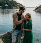 Couple embracing by a body of water with a scenic background