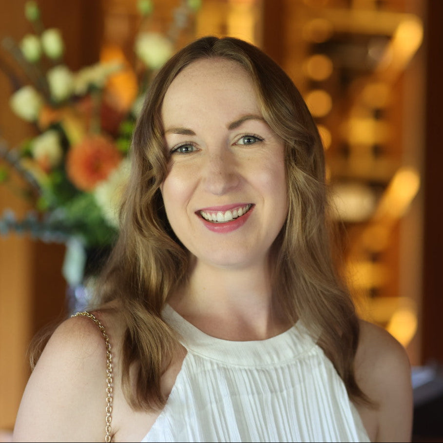 Woman in a white dress standing in a warmly lit room with decorative elements.
