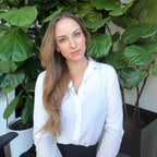 Evelyn Martin in a white shirt standing in front of green plants