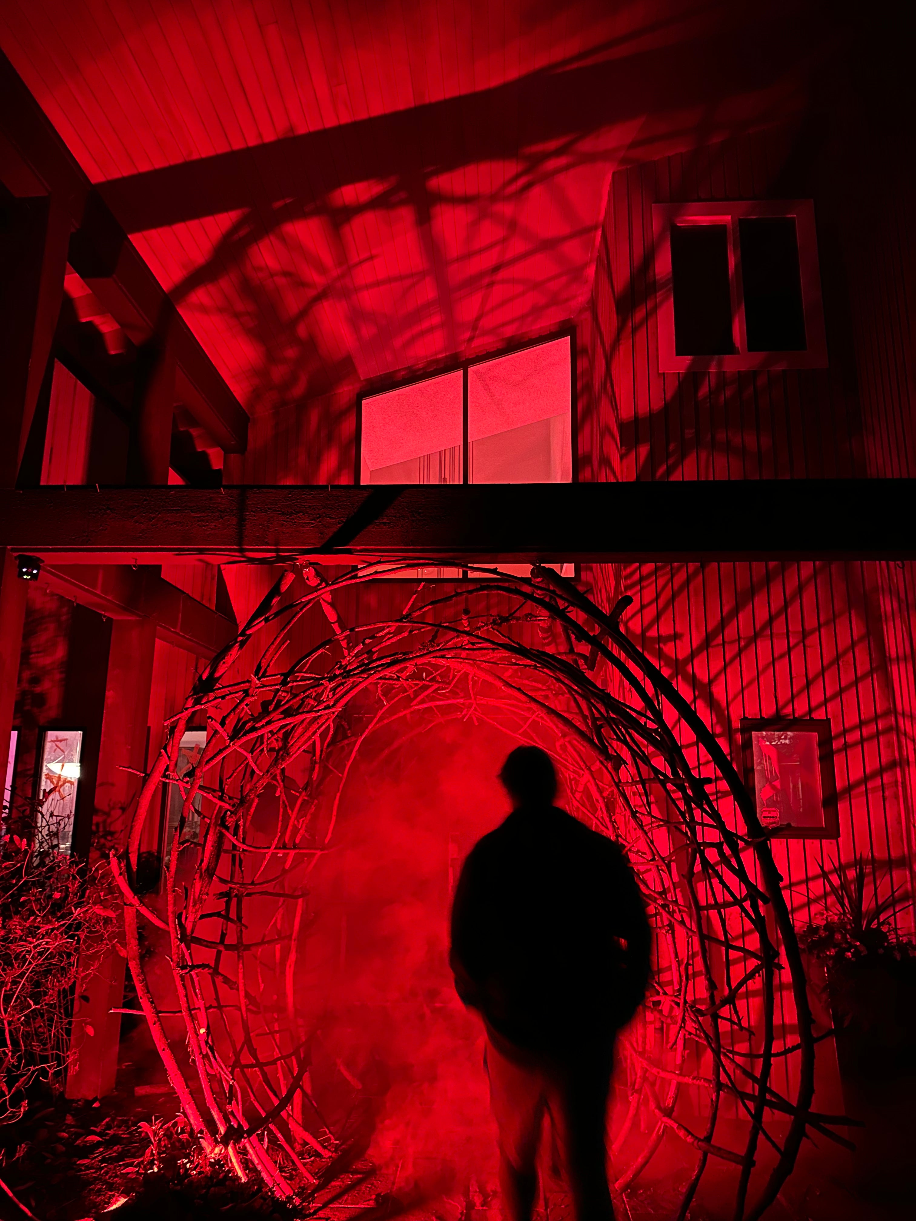 Red-lit interior of a building with a person standing in front of a large circular metal object.