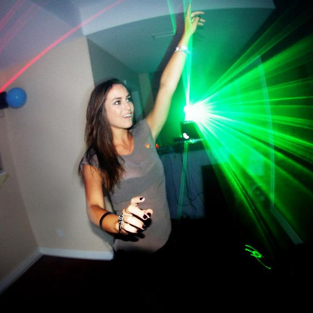 Woman holding a green laser pointer in a room with laser lights