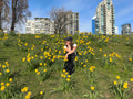 Grassy hill covered in yellow flowers with city buildings in the background
