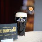 Guinness beer glass with a St. Patrick's Day card on a table.