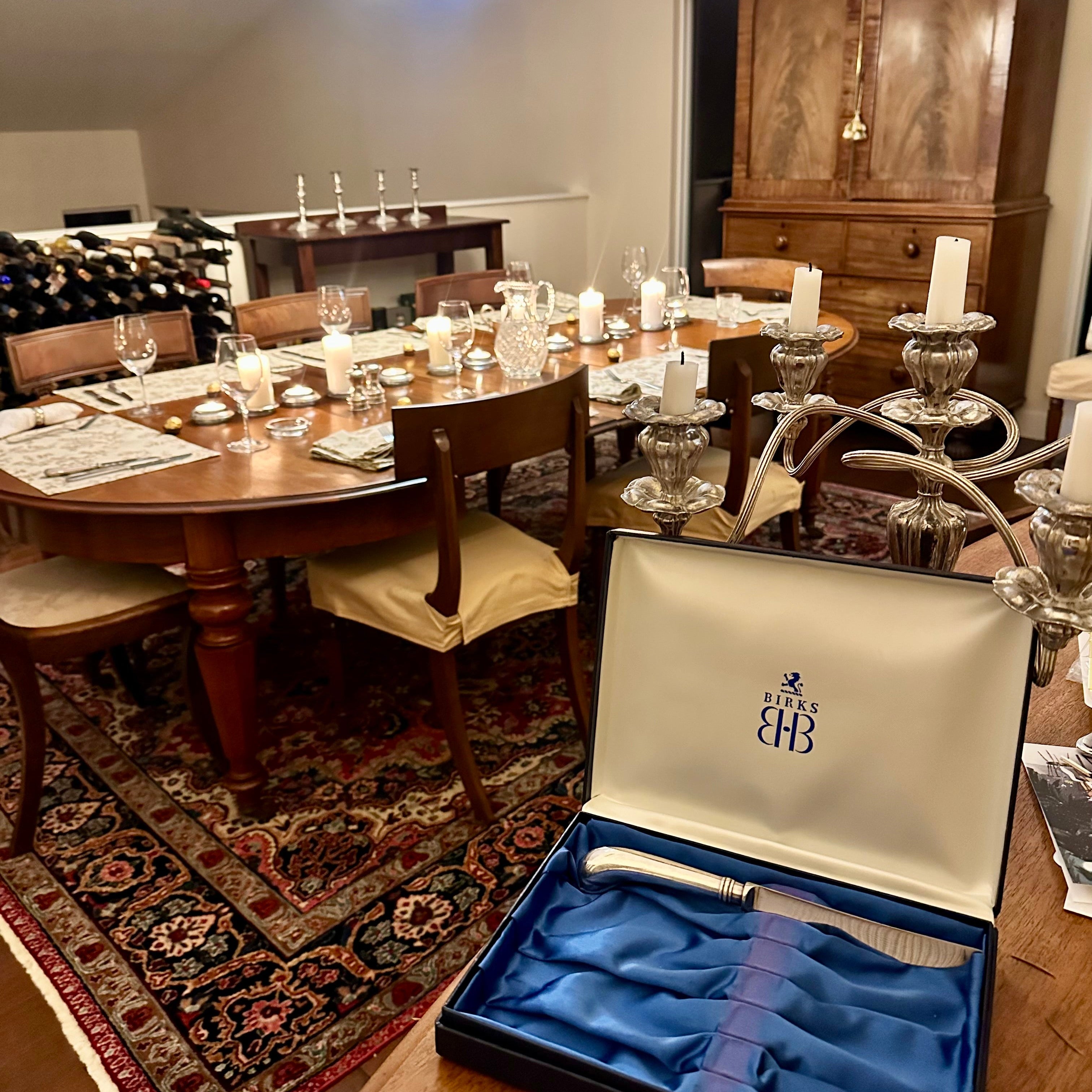 Dining room with a table set for a meal, wine glasses, and a cutlery set in an open box.