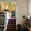 Staircase leading to an upper level with a piano and bookshelf in a home setting.
