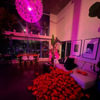 Decorative setup with red roses, framed photos, and a pink spherical light fixture.