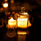 Bottle of Bulleit Bourbon Whiskey with a glass on a dark background with candles