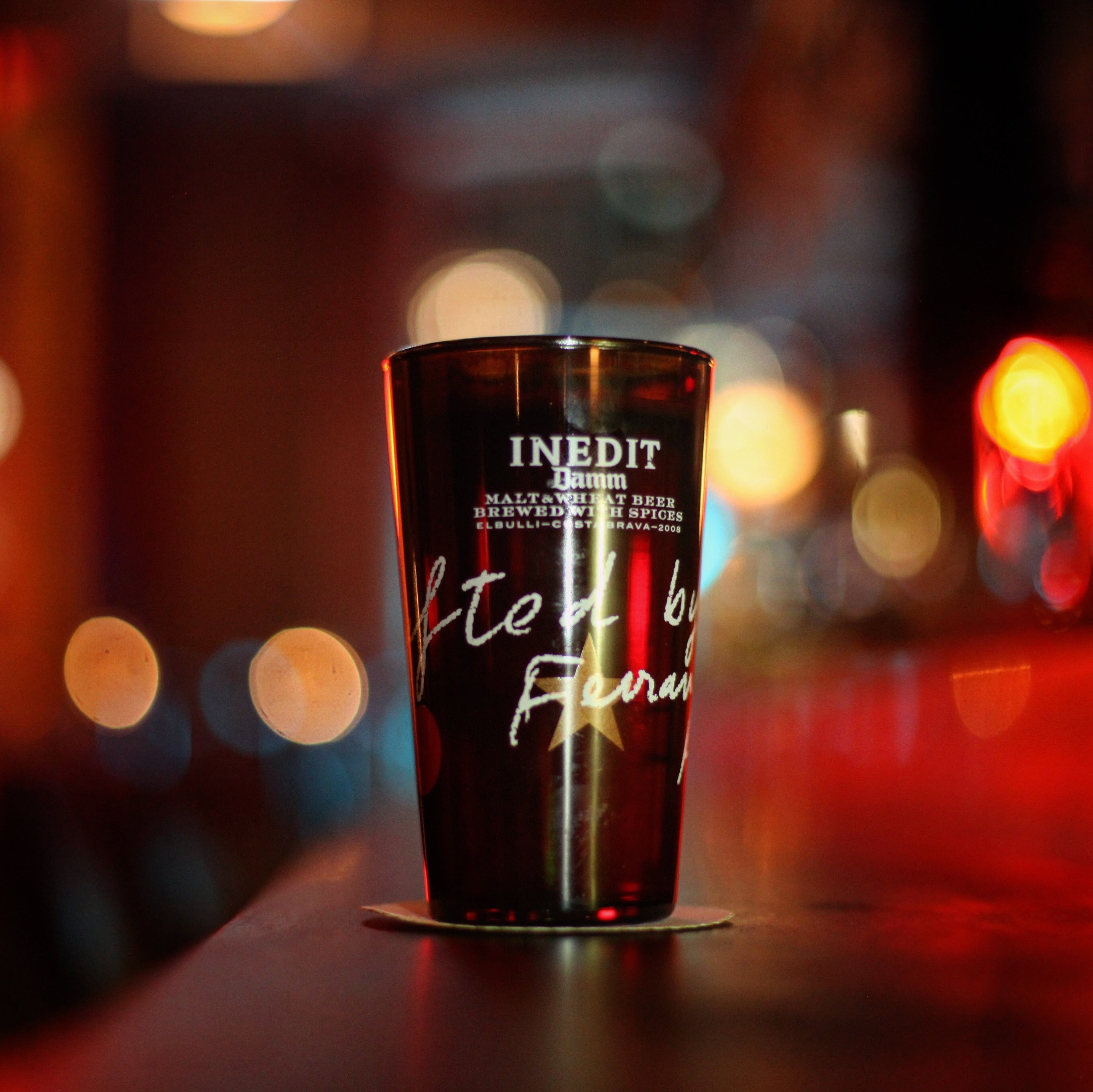Dark glass with 'INEDIT' branding on a blurred street background