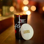 Black cup with white label on a bar counter with blurred lights in the background