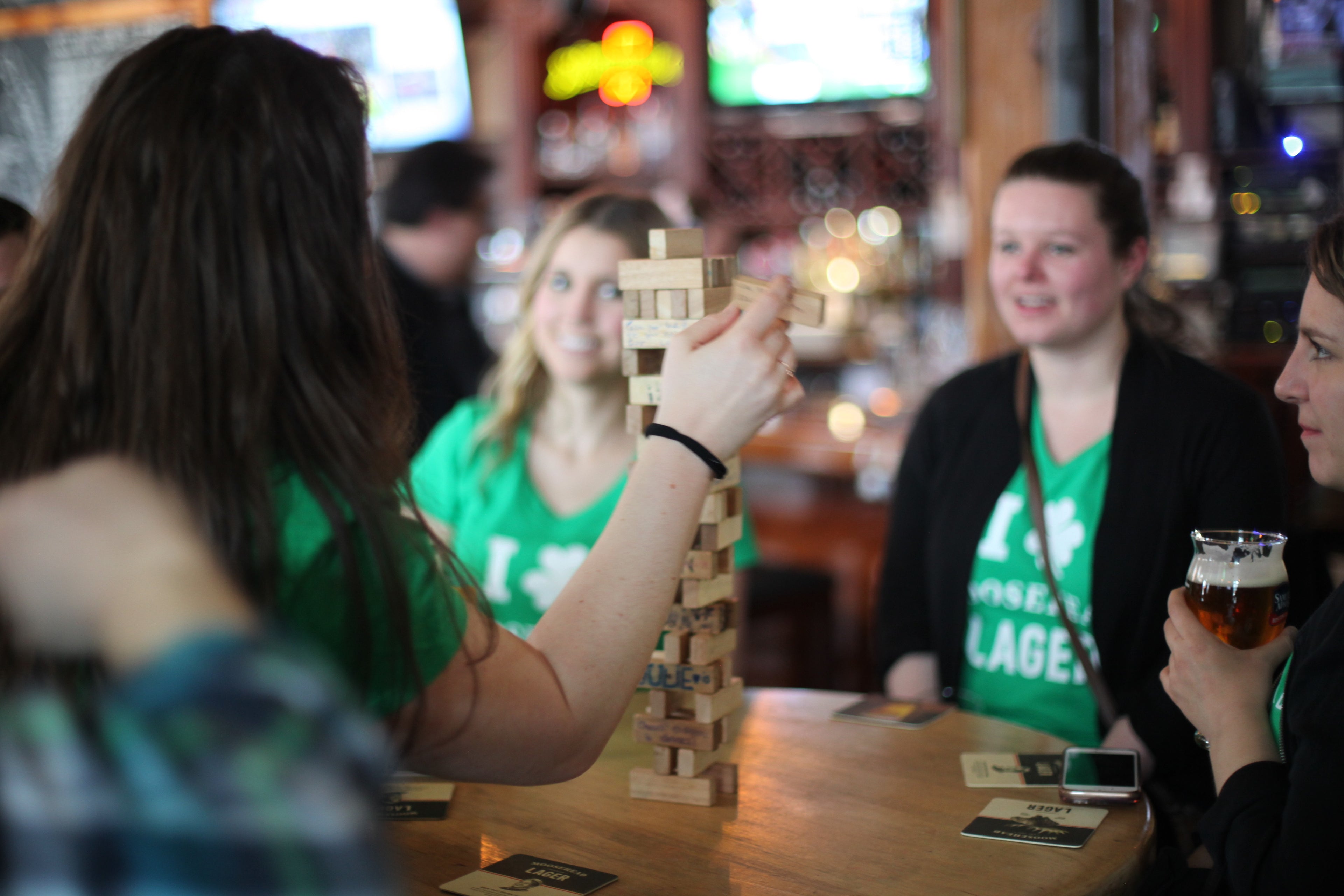 People playing a game of Jenga at a bar with a festive atmosphere.