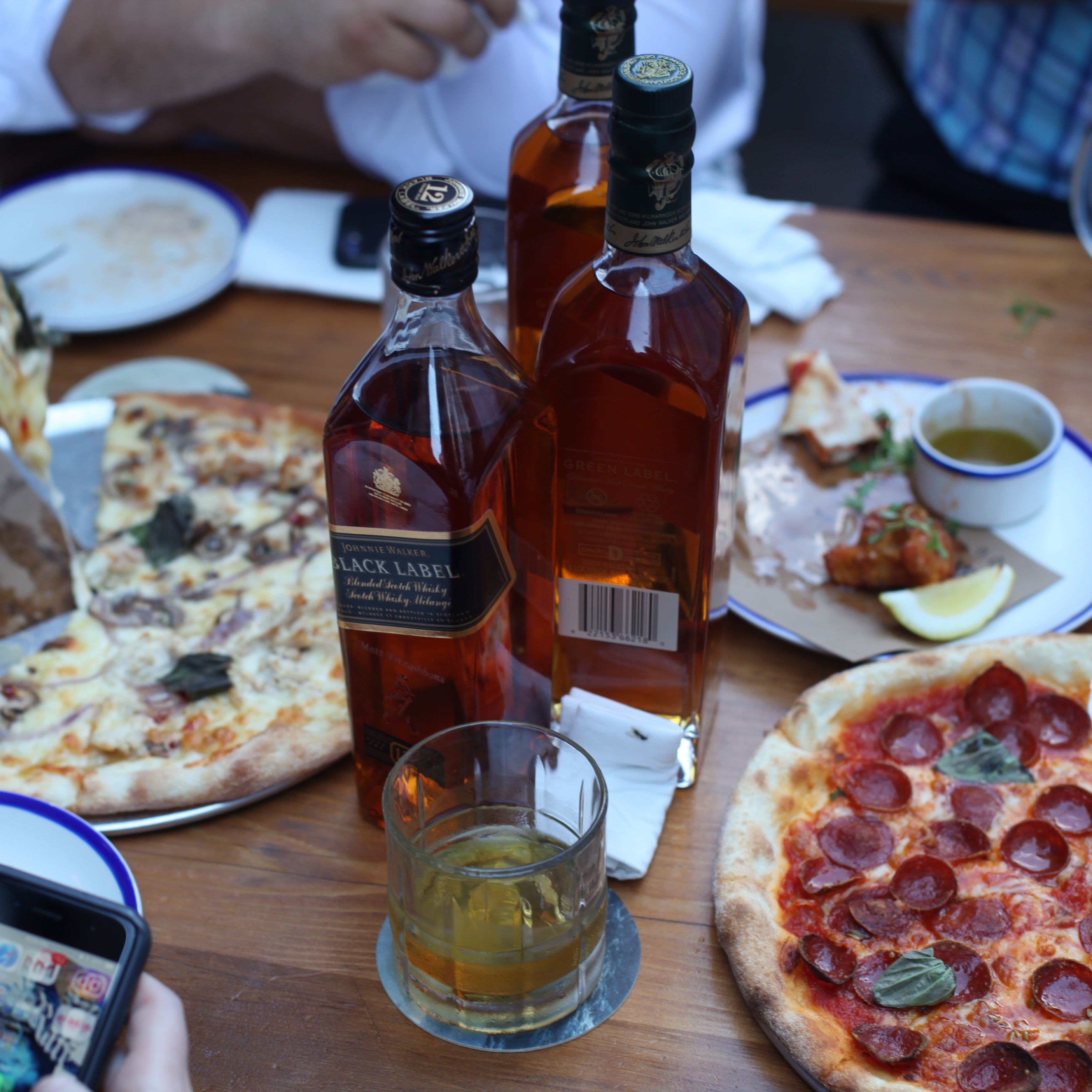 Table with pizza, drinks, and people eating in a casual setting