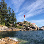 Lighthouse on a rocky outcrop with trees on the pacific north west coastline 