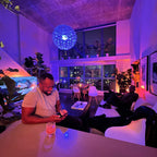 Man sitting at a table in a modern interior with blue lighting and city view.