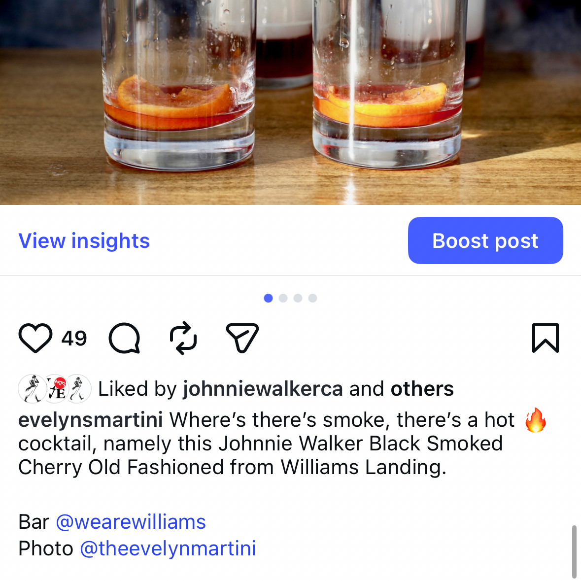 Two cocktails with orange slices in clear glasses on a wooden surface, with a blurred background.