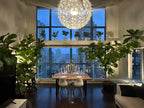 Modern dining room with a large window view, chandelier, and decorative plants.