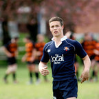 Person in sports uniform on a field with blurred teammates in the background