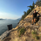 Rocky cliff overlooking a body of water with mountains in the distance.