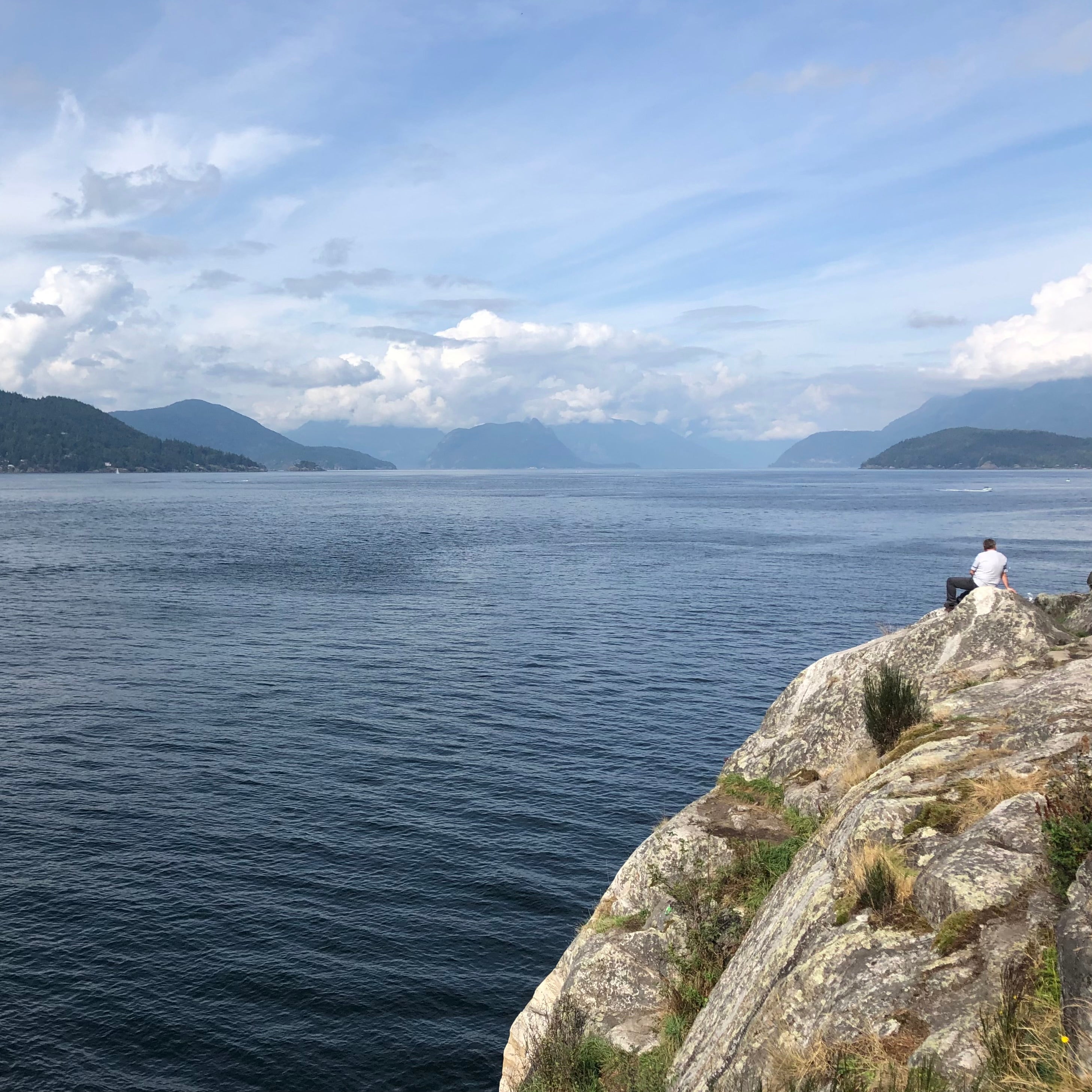 Rocky outcrop overlooking a large body of water with mountains in the background.
