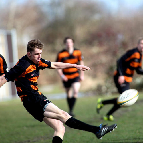 Rugby player in action with teammates and ball on a field