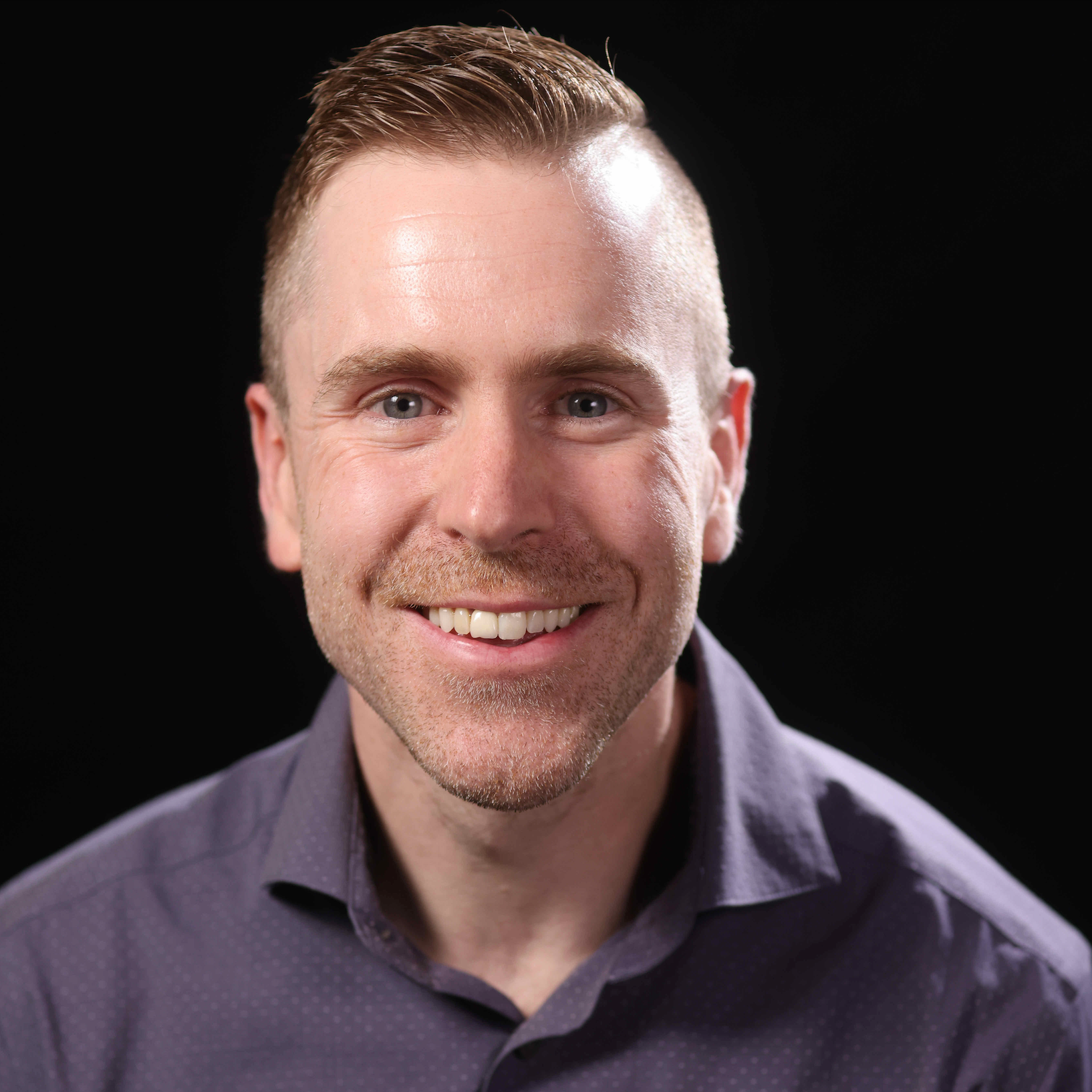 Man wearing a purple shirt against a black background