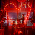 Woman standing in a modern kitchen with red lighting and cityscape view