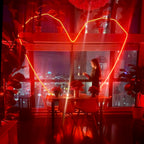 Woman standing in a modern kitchen with red lighting and cityscape view