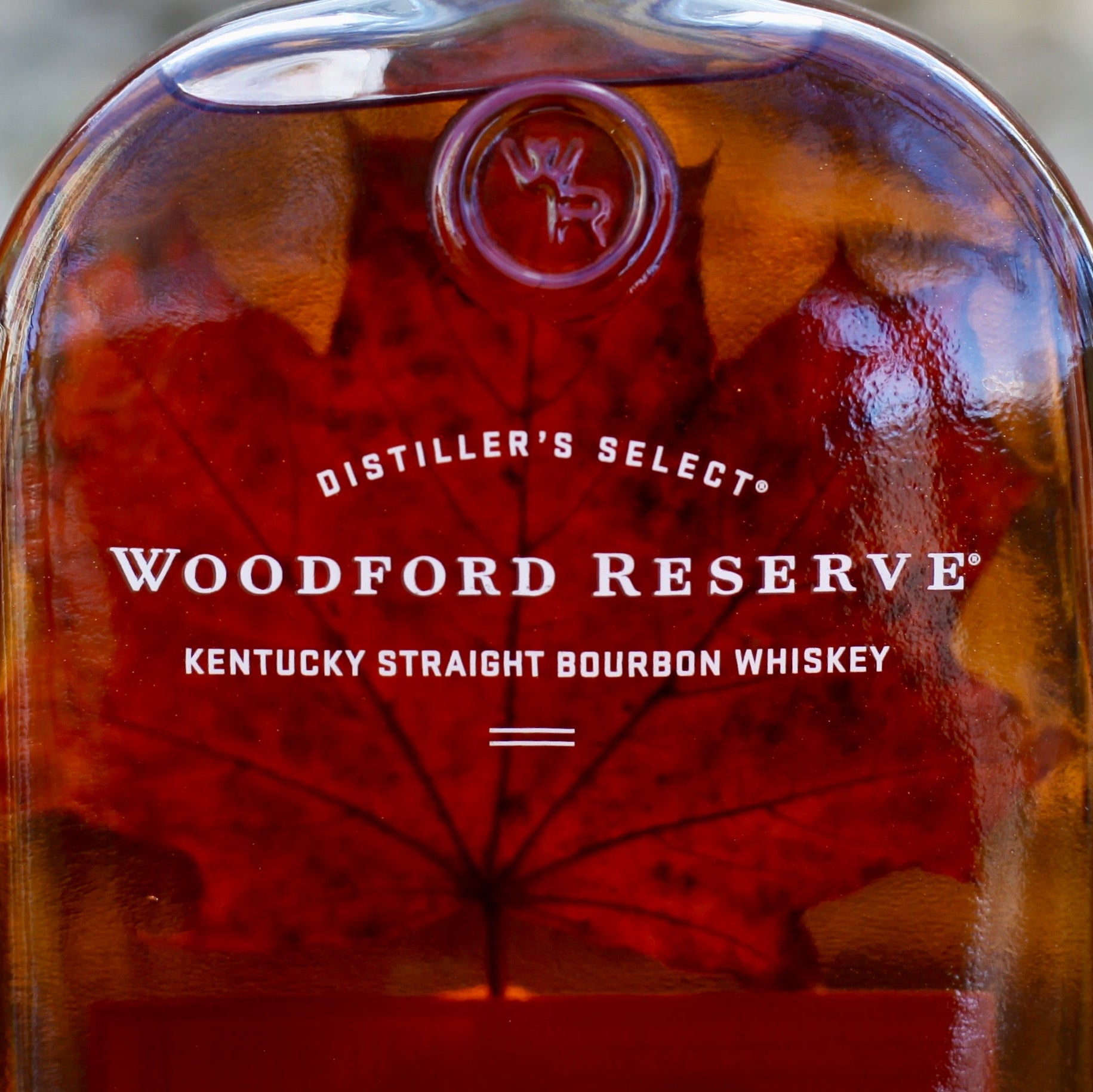 Woodford Reserve bourbon whiskey bottle with a blurred natural background
