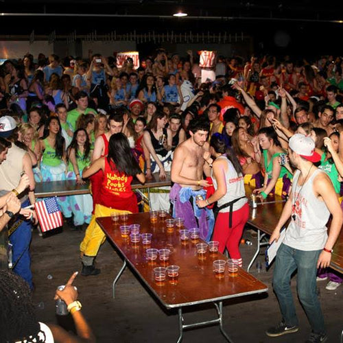Crowd of people at a lively event with tables and decorations.