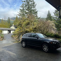 Black SUV parked on a driveway with trees and mountains in the background