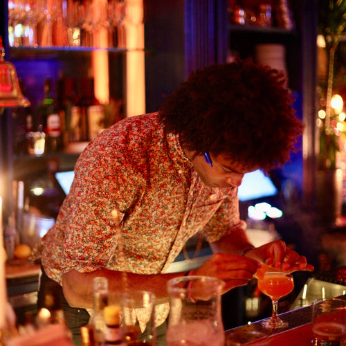 Person working behind a bar counter in a dimly lit bar setting