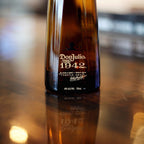 Don Julio 1942 bottle on a reflective surface with a blurred background