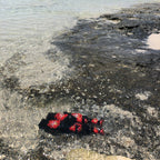 Red and black objects on a textured surface with water in the background