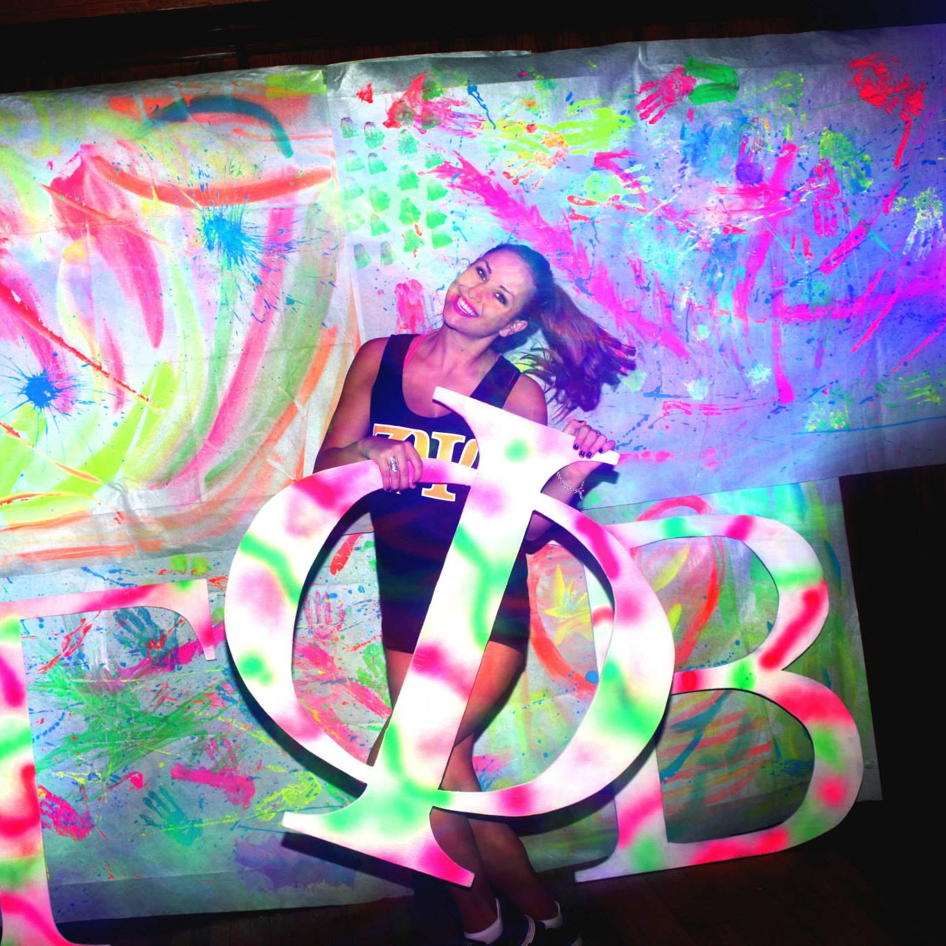 Woman posing with a large peace symbol in front of colorful abstract art