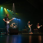Band performing on stage with instruments under colorful lights