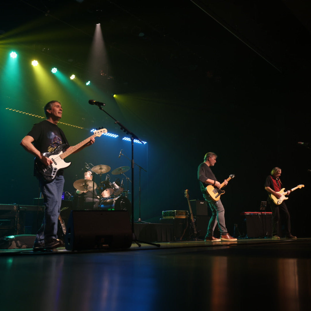 Band performing on stage with instruments under colorful lights