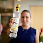 Person holding a bottle of Ketel One vodka in an indoor setting