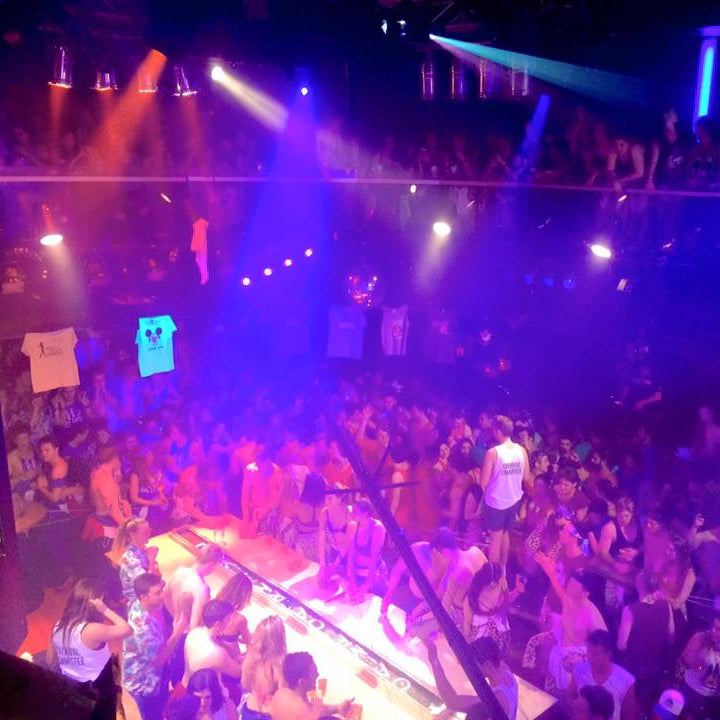 Crowded nightclub with vibrant lighting and people enjoying themselves.