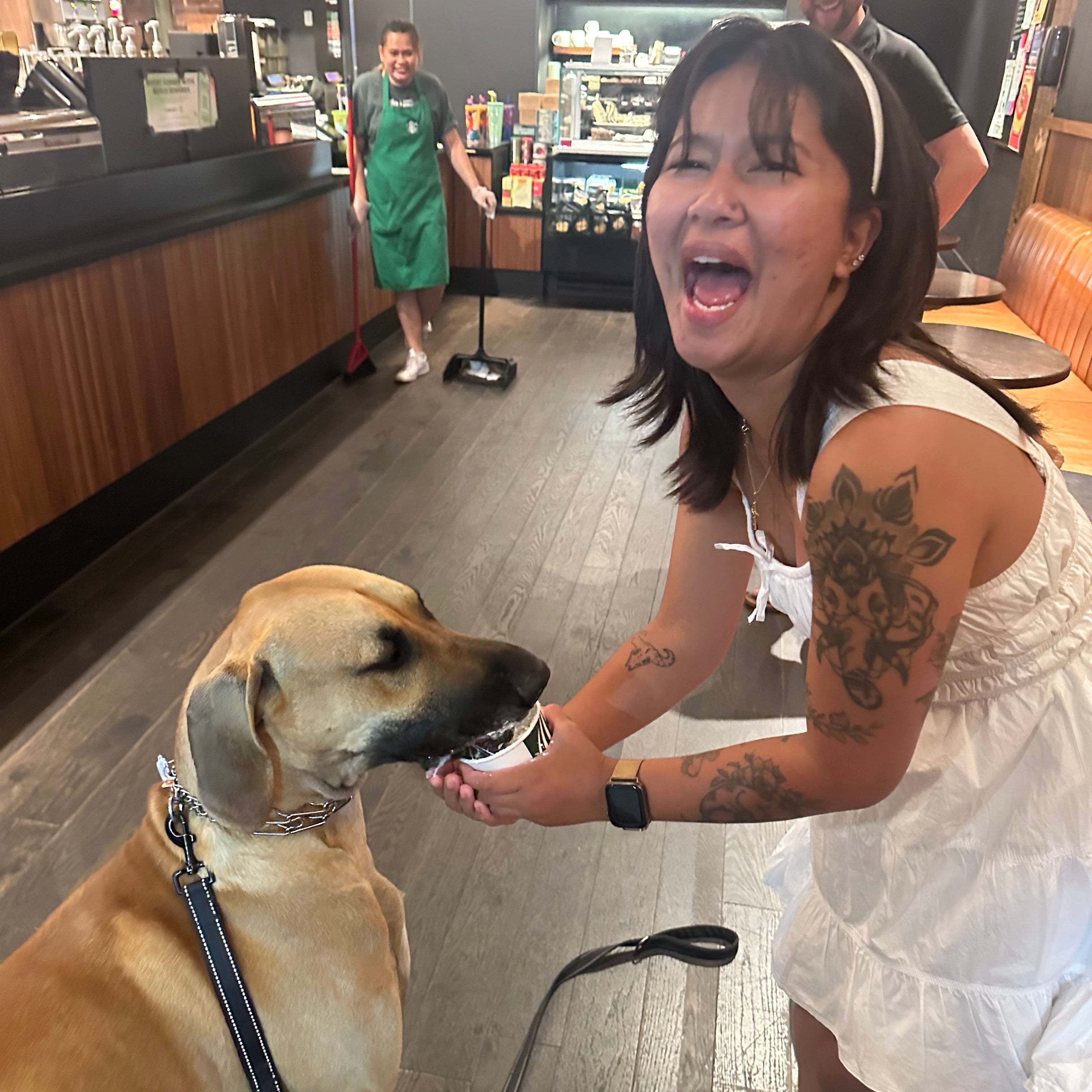 Woman with tattoos petting a dog in a casual setting