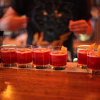 Row of red cocktails with orange slices on a bar counter, blurred background